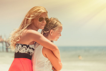 Naklejka premium Mom and daughter stay hugging on the sea and look at the water with dreams.
