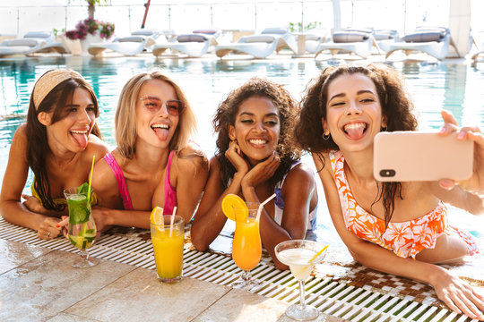 Four cheerful young women in swimwear taking a selfie