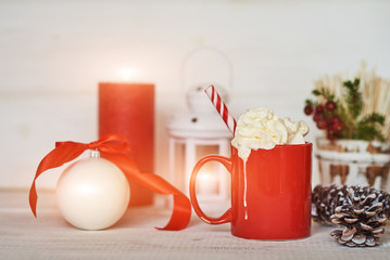 Red mug with hot chocolate with melted marshmallow and whipped cream. Winter hot drink. Christmas hot chocolate or cocoa with marshmallow on white background with christmas decorations.