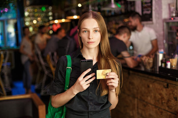 young woman with a credit card and stands in a cafe