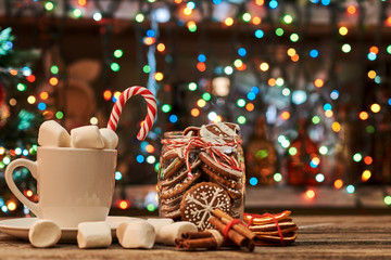 Cup of coffee with cinnamon and dried orange on a Christmas light background.