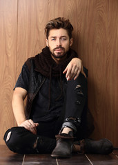 Handsome mature man sitting by the brick wall. Men's fashion.