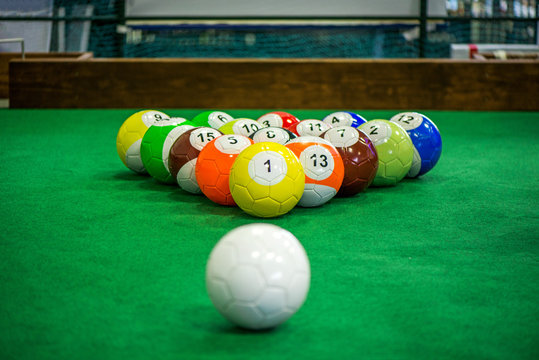 Shot of foot pool balls standing on green table. Foot Pool is the hybrid combination of pool and soccer. Big billiard balls. 

