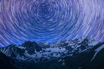 rotation of star tracks in the night sky over mountains with snow background illustration