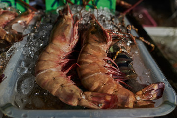Raw giant shrimp  for sale at a fish counter. Close up fresh raw shrimps on display on ice in fisherman shop. Whole tiger prawns on ice. The market scene. Shot with a selective focus.