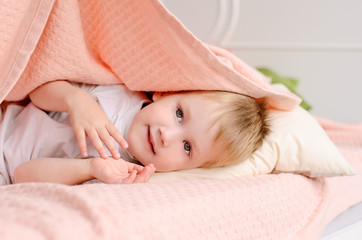 Obraz na płótnie Canvas boy lies on a bed under a blanket