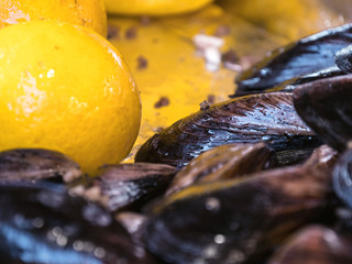 Cooked mussels in a bowl with lemon. Stuffed mussels and lemon. Mussels close up on a tray in the window with lemon. Tray with mussels and lemons. Street trade.