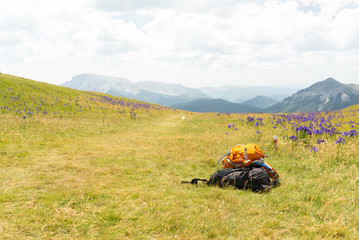  Vista de un camino de montaña con dos mochilas en su lado derecho y montañas en el horizonte. Concepto senderismo. Pirineos, España.