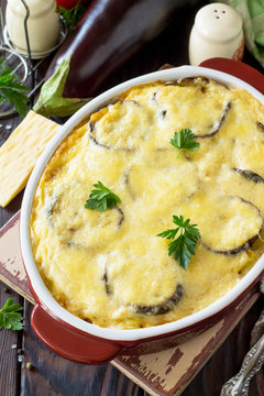 Eggplant casserole with beshamel (moussaka) - a traditional Greek dish on the kitchen wooden background. Copy space.