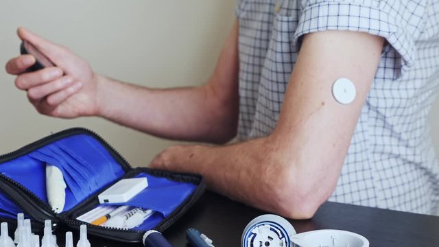 A man using a non-invasive glucose meter to measuring glucose level blood