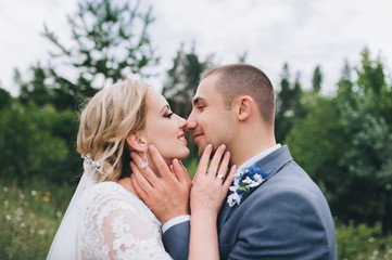 Portrait of happy newlyweds close-up against a background of coniferous forest and green pines. Wedding concept. A stylish bride and a sweet bride.