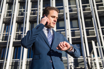 Serious businessman checking time talking on phone 