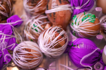 Easter eggs prepared for dyeing in onions peels, decorated with natural fresh leaves, plants, rice, colorful fabric and tied with white threads. Eggs laying in wicker wooden basket full of green grass