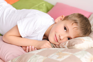 Obraz na płótnie Canvas boy lying on the bed in pillows