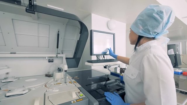 Biochemical analyzing machine is being managed by a lab worker at a pharmaceutical production facility.