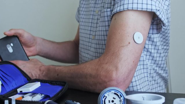 A man hands brings to the hand the smartphone for measuring glucose in the blood