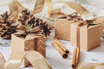 Christmas and New Year holidays concept. Gift boxes with ribbon, fir branch, cones, cinnamon on white knitted background