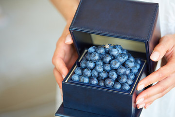 A magnificent ring with diamond and blueberries in a jewelry box. A gift in women's hands.