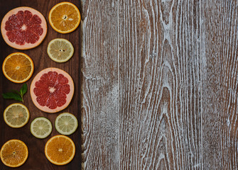 Variety sliced citrus fruit orange, grapefruit, lemon on a brown wooden board. Top view. Copy space.
