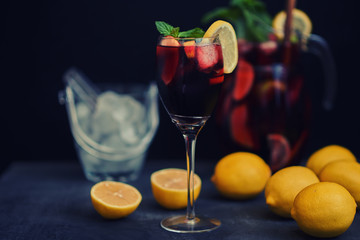 Sangria and ingredients. Refreshing sangria or punch with fruits in wine glasses and pitcher. Red wine sangria with ice. Tradbcional spanish  sangria on the rustic wooden table, copy space.