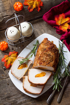 Meat roll (roulade) with with apricot stuffing and spices on a kitchen wooden table. Thanksgiving day appetizer.
