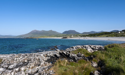Fototapeta na wymiar Renvyle beach, taken from the rocks, showing blue sky and surrounding mountains in summer.