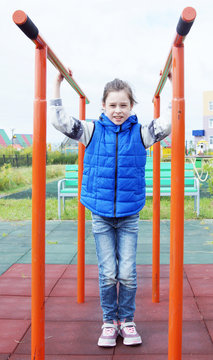 Little girl stands in the football gate as a goalkeeper and wants to catch the ball in her hands
