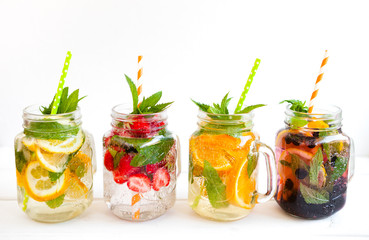 Homemade iced lemonade with mint, summer fruits and berries in a mason jar. Copy space background