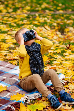a child with a camera, a boy takes pictures in the fall