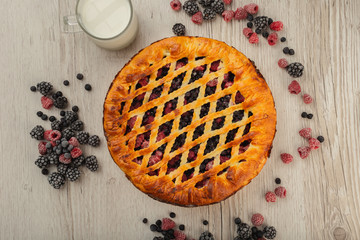 Berry pie on a wooden background with ingredients.