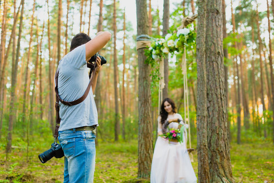 Photographer taking pictures of the bride on a rope swing