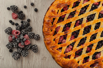 Berry pie on a wooden background with ingredients.