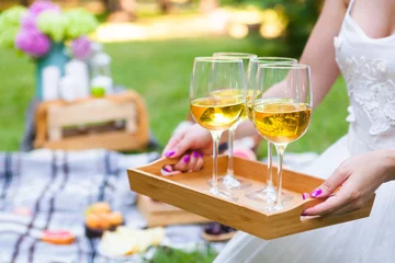 Keuken foto achterwand Picknick Jonge vrouw met een schotel met glazen witte wijn op picknick zomerfeest, close-up