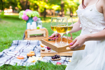 Young woman holding a dish with glasses white wine at picnic summer party, close up