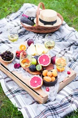 Poster Picnic background with white wine and summer fruits on green grass, top view © yatcenko