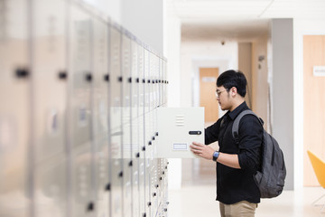 Student opening his locker at college - 218039127