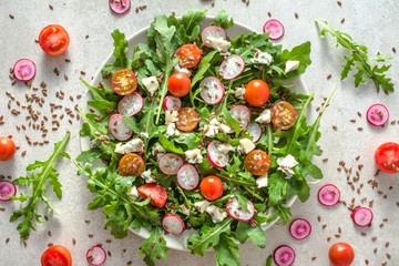 Fresh vegetable salad with arugula, tomato and feta cheese. Healthy food, vegetarian lunch on plate.