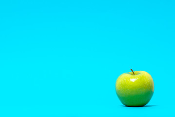 Ripe green apple isolated on blue background, copy space