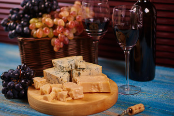 Platter with delicateness Roquefort slices near to chardonnay glasses and wicker basket with colorful fruit.Food and drink for drink in rustic style