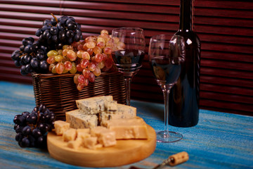 Yummy slices of Danablu cheese on board next to organic juicy grape and bottle of soft alcohol.Wine degustation with delicious food.