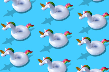 Inflatable unicorn pool toy pattern onl blue background. Minimal summer concept.