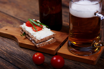 Closeup image of delicious snack with sliced bread, cheese cream, healthy greens, cherry tomato pieces lying on plate for tasteful beer.