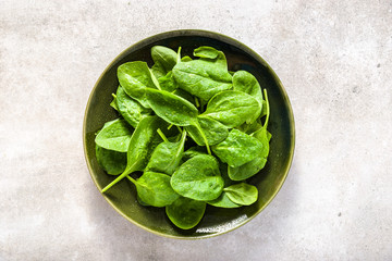 Fresh spinach. Green vegetable leaves on plate, healthy food, vegan diet concept.