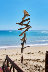 Beautiful decor made from variety natural seashells and corals, hanging on the beach on the turquoise ocean background.  Vacation and travel concept.
