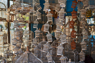 Many different sizes, colorful, wooden cages for birds. The store for selling cages for birds is completely filled with various colorful handmade cages.  Multicolored background. Selective focus.
