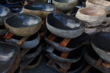 Handicrafts sinks, made of natural stone stacked in a warehouse. Stack of stone handmade bowls....
