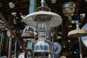 Fototapeta premium Vintage lamps. Various vintage objects for sale at a indoor flea market. View of a display full of interesting old things for sale. Many groups of vintage assorted second-hand objects.