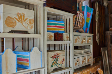 Fototapeta na wymiar View of a furniture of drawers. Shabby vintage style interior, furniture from rustic whitened wood. Nightstand made of natural wood with three drawers with handles and shelves of untreated wood.