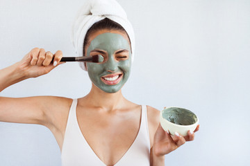 Young beautiful woman in face mask of therapeutic blue mud. Spa treatment, self care and healthy skin - 218041520