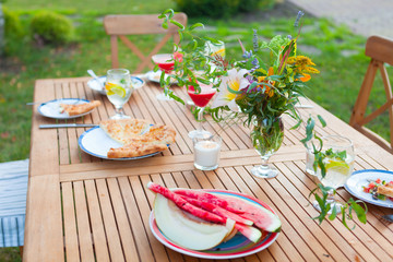 Family outdoor dinner in the garden in summer at sunset. Picnic food and drink concept